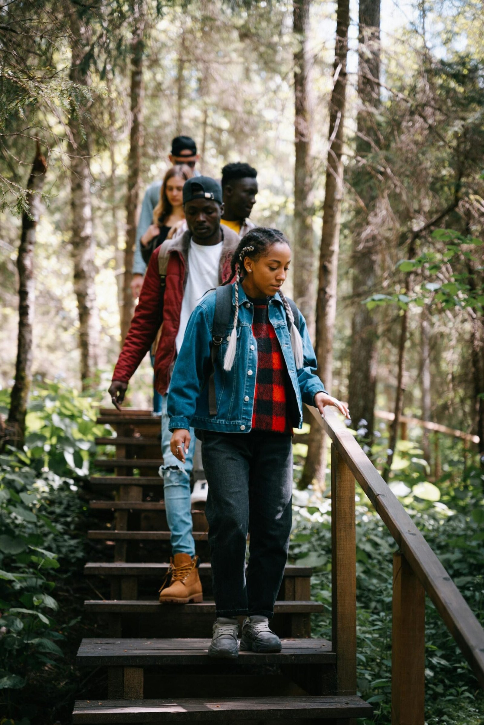 pexels-photo-9630175-9630175 A diverse group of friends walking down wooden stairs in a lush forest setting.